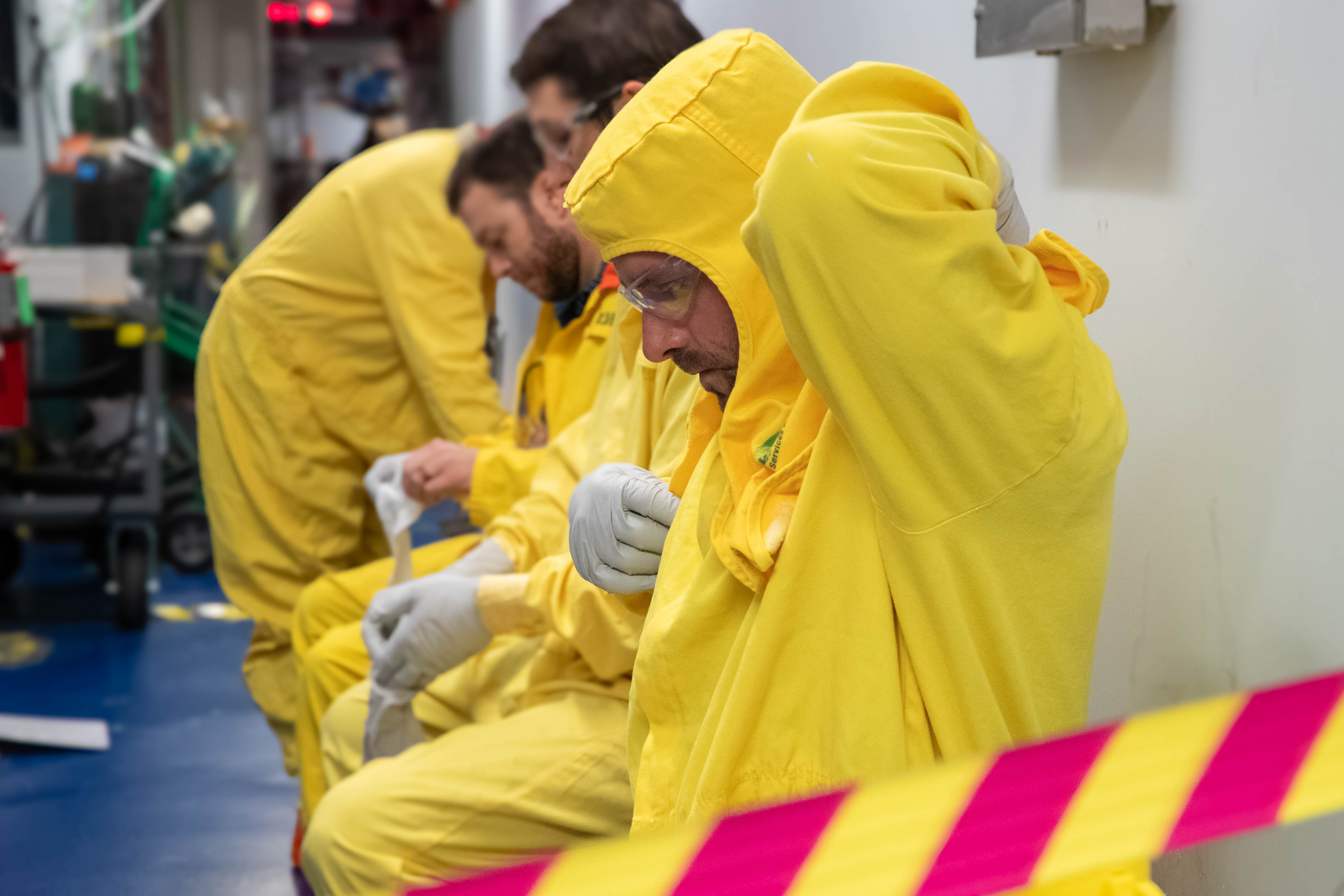 Workers wear respiratory protection and protective clothing to shield themselves from potential radiological hazards. 